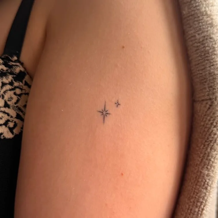 Zwei kleine Sterne als Fine-Line-Tattoo am Oberarm