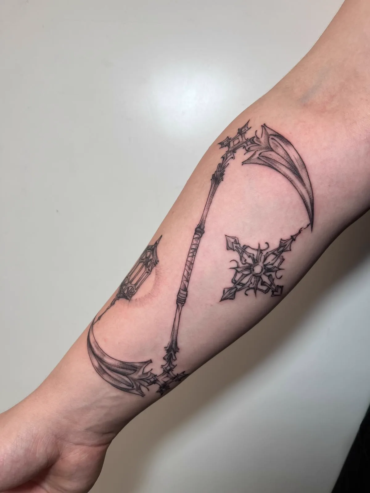 Sense und Ornamentkreuz am Unterarm